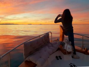 chica contemplando la puesta sobre un barco en Dénia